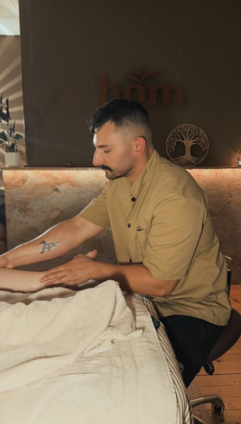 Marc-Antoine, masseur bien-&ecirc;tre de HOM Meyri&eacute;, effectue un massage des pieds sur un client dans son studio